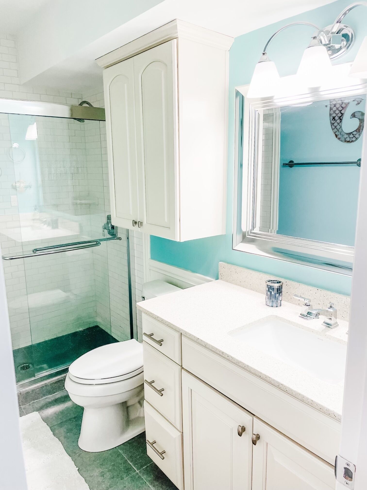 A bathroom with a toilet, a sink, a mirror, and a shower area.