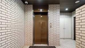 A hallway with a brown elevator, white tiled walls, and a door with a handle. - Akasaka Roppongi area with elevator Quiet high-class residential apartment close to train station (港区)