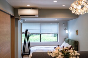 A bedroom with a bed, a window with blinds, a standing lamp, and an air conditioning unit. - Akasaka Roppongi area with elevator Quiet high-class residential apartment close to train station (港区)