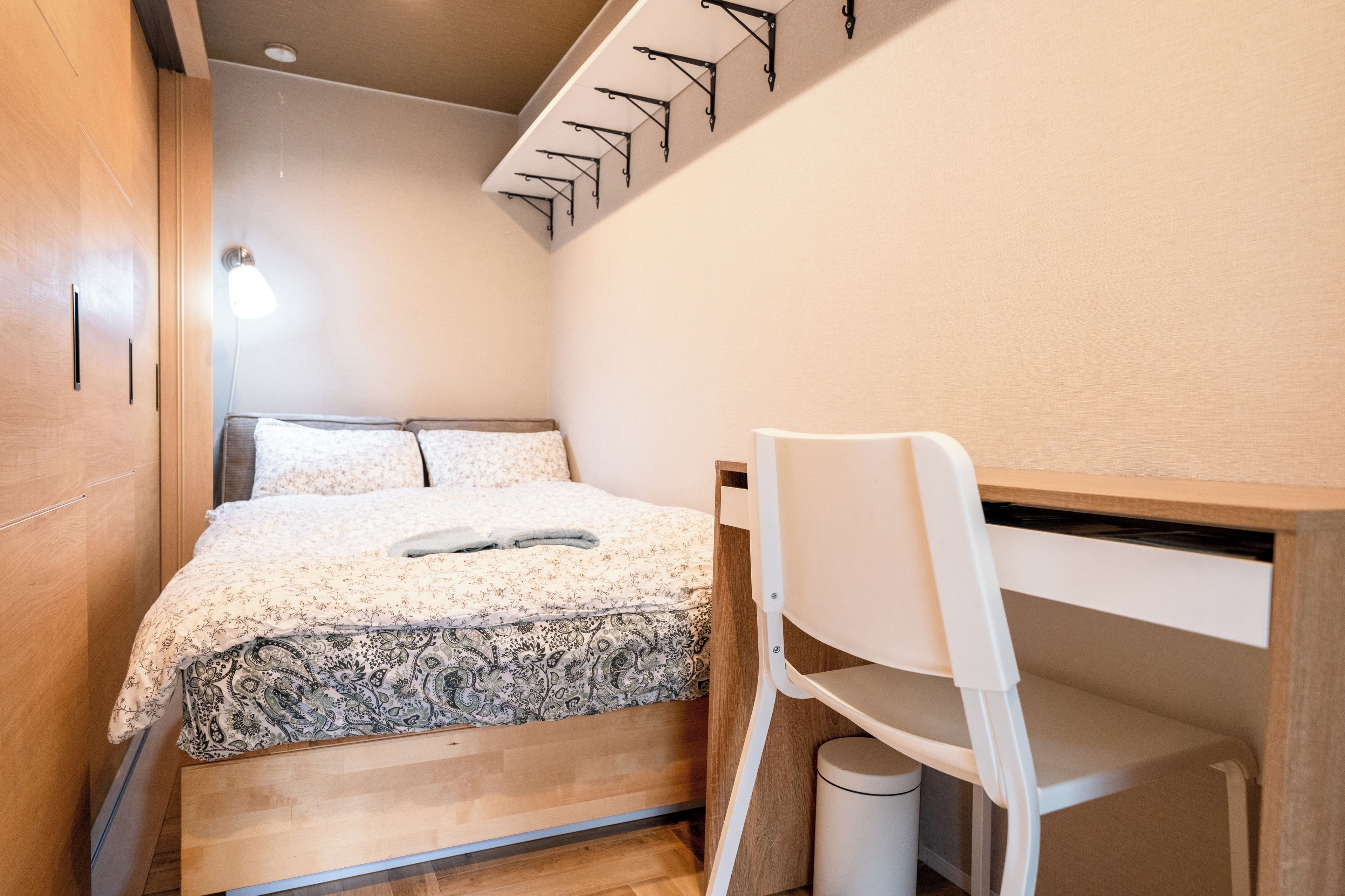 A compact bedroom with a bed, a desk, and a chair.