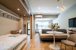 A modern hotel room with a bed, sofa, and a small table with a vase of flowers. - Akasaka Roppongi area with elevator Quiet high-class residential apartment close to train station (港区)