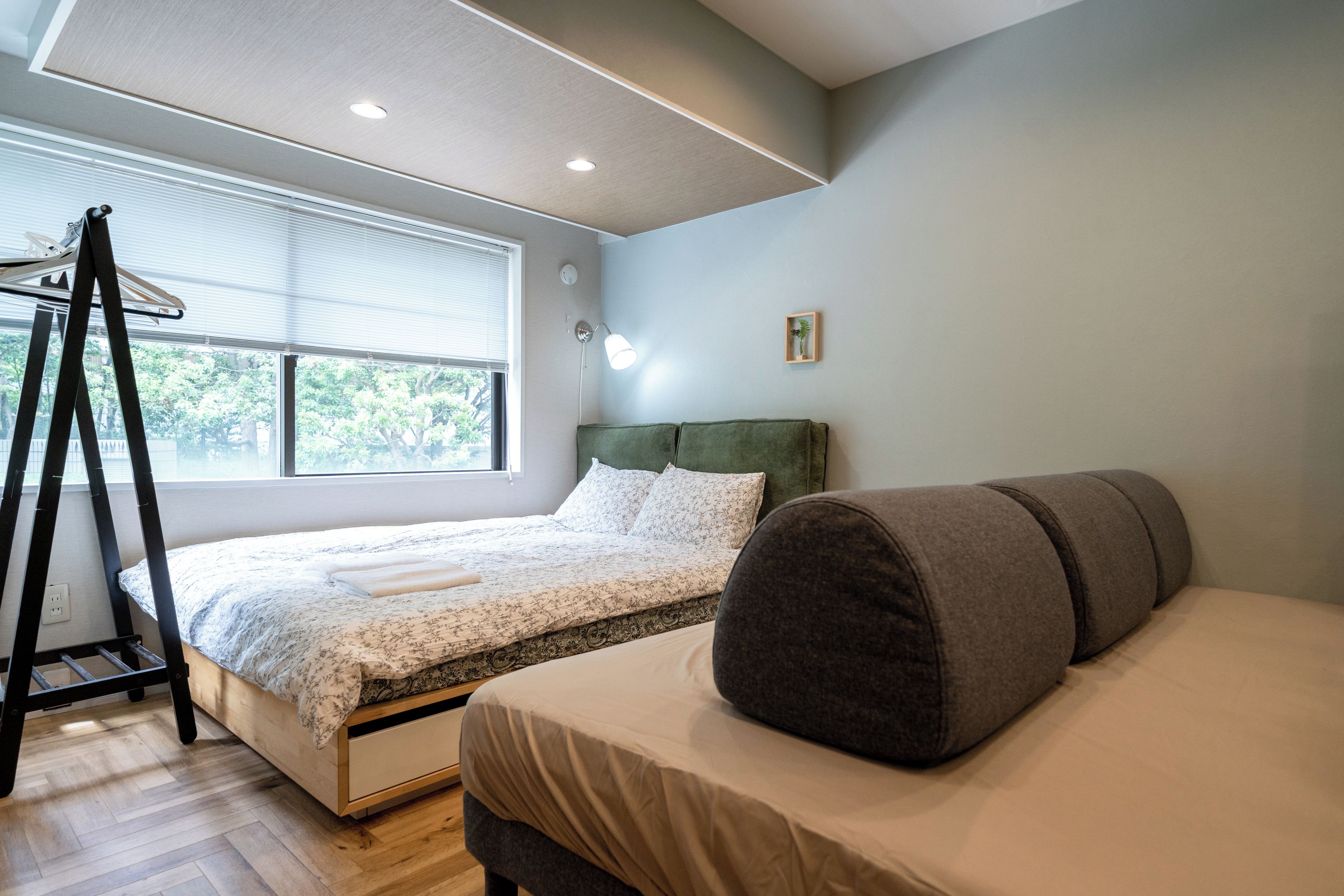 A bedroom with a bed, a bedside table, a lamp, and a window with blinds.