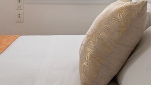 A bedroom with a window, a bed with white bedding, and a decorative pillow.