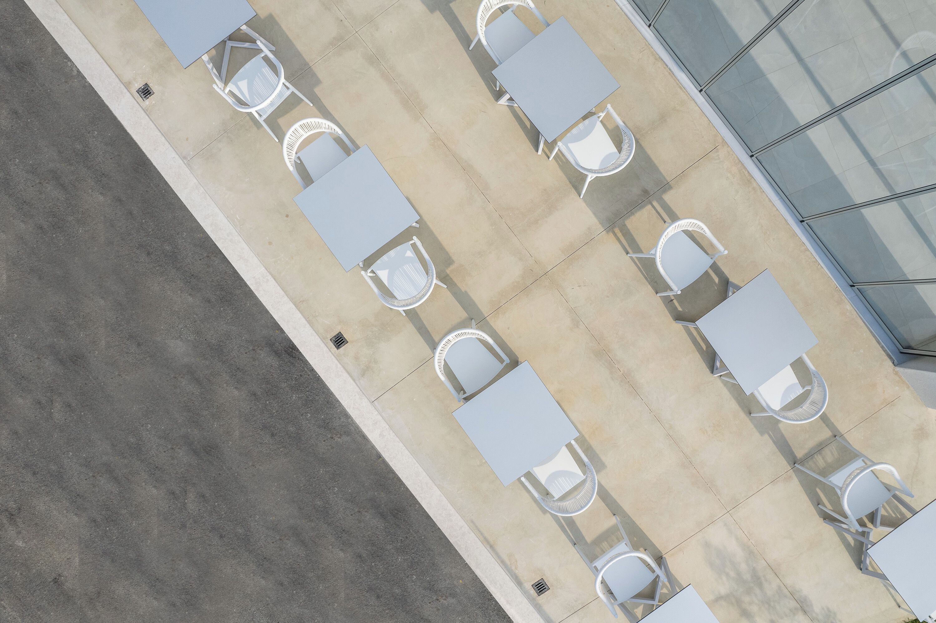 Vue aérienne d’un espace patio avec des tables et des chaises blanches disposées en rangée.
