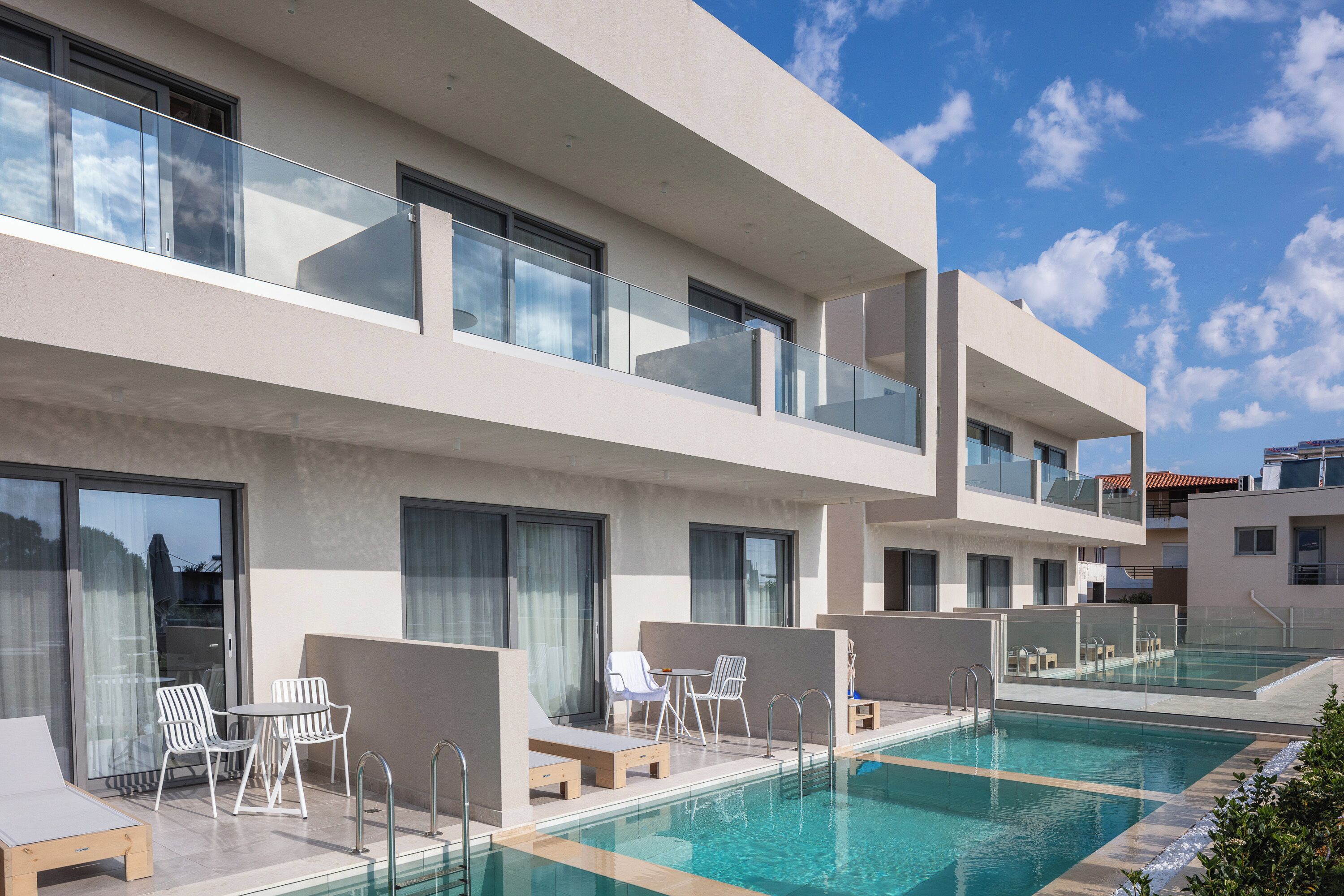 Un hotel moderno con piscina en la azotea, mobiliario exterior y vistas despejadas del cielo.