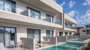 Un hotel moderno con piscina en la azotea, mobiliario exterior y vistas despejadas del cielo.