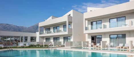 Un hôtel moderne doté d’une piscine, de nombreux balcons et offrant une vue sur les montagnes.