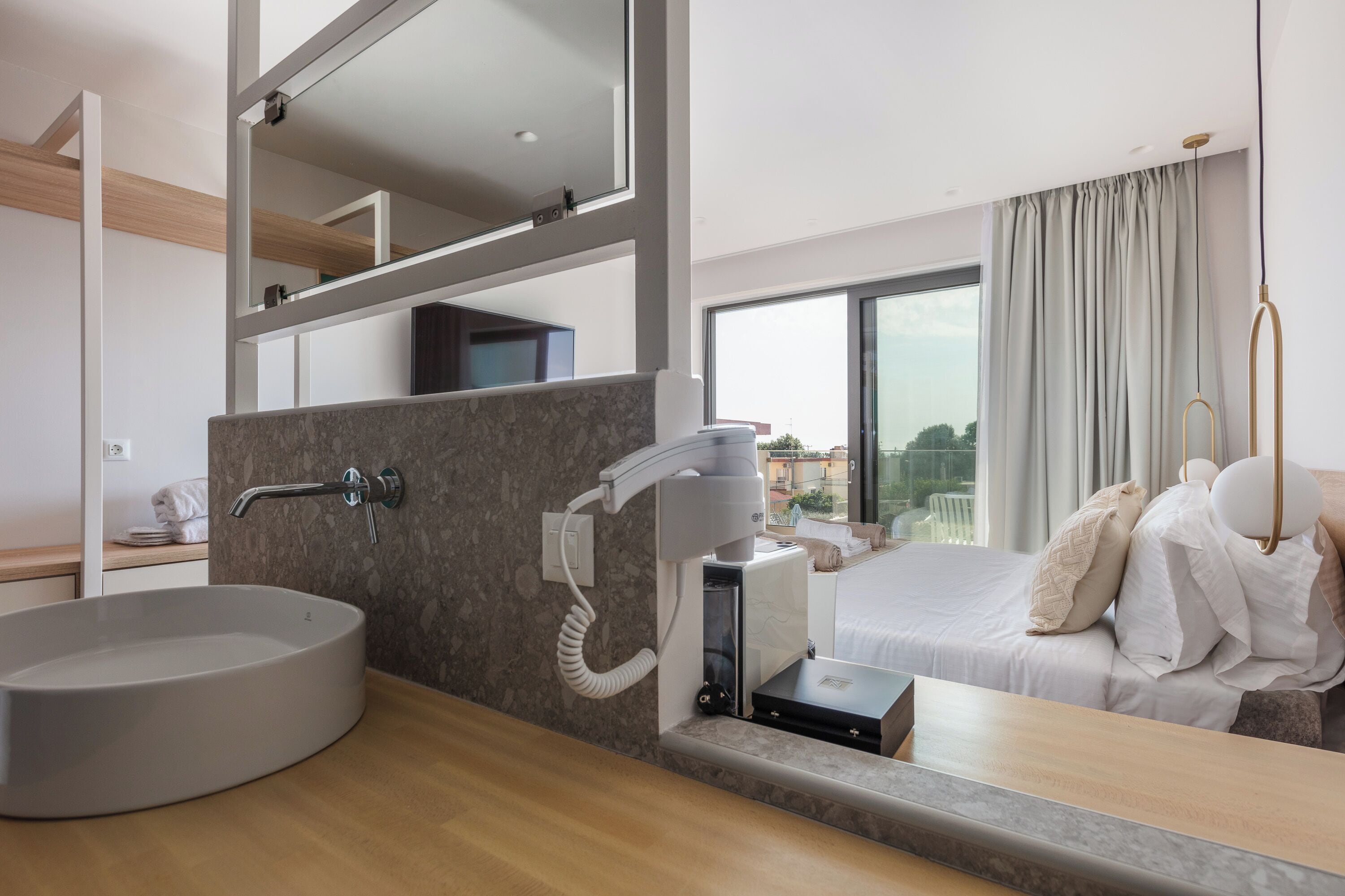 A modern bathroom with a large, round sink, a hairdryer, and a mirror.