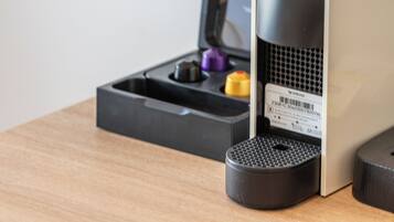 Una cafetera sobre una mesa de madera, con una bandeja negra y una caja al fondo.