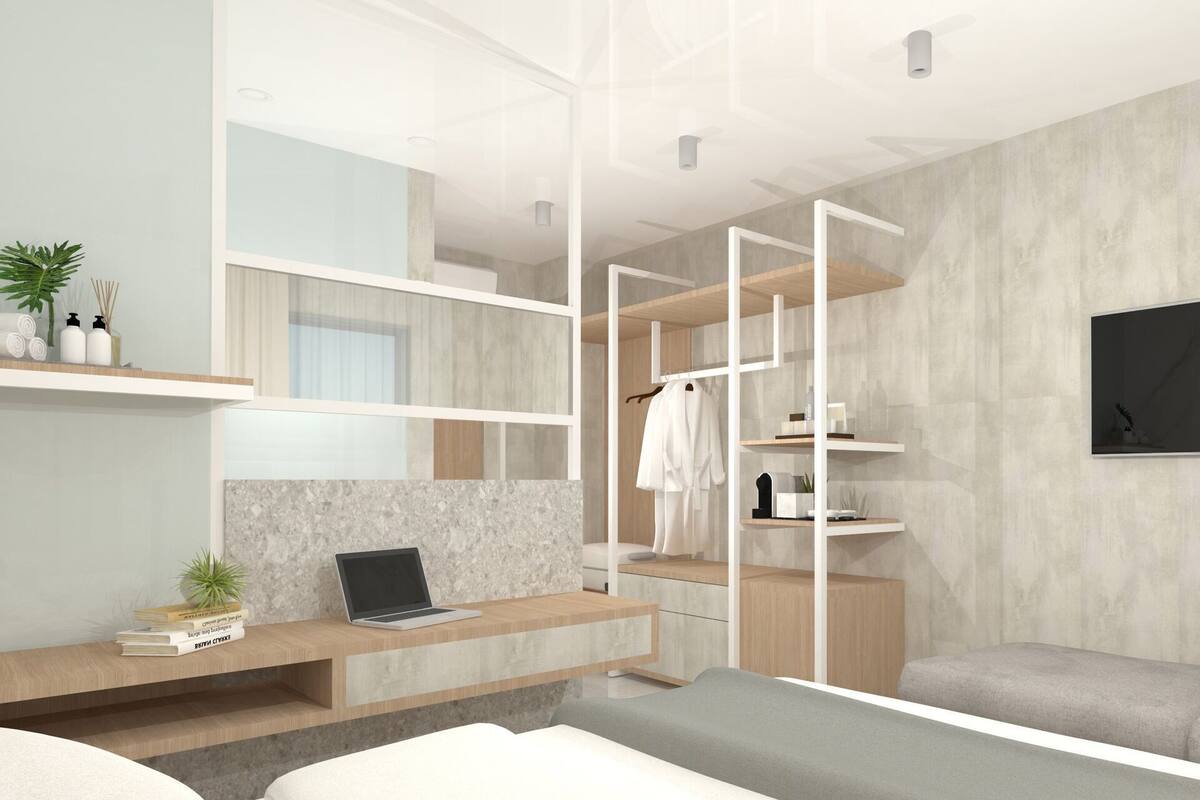 A modern bedroom with a bed, a desk, a laptop, a TV, and built-in shelving.
