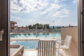 A view of a swimming pool with lounge chairs and umbrellas, a table, and a bench. - Nima Boutique Hotel (Apokoronas)