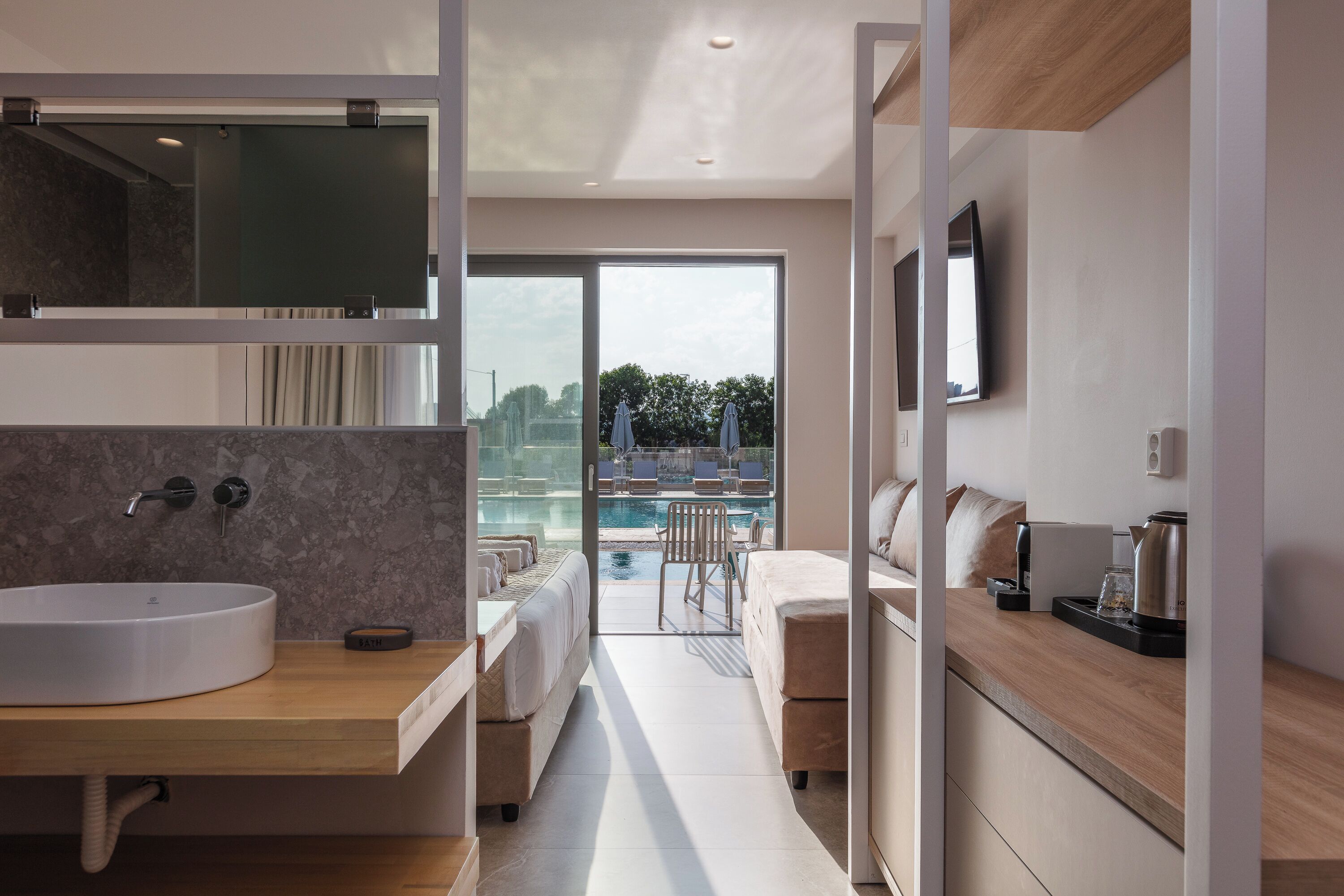 Un baño moderno con un lavamanos grande, un espejo y vistas a la zona de la piscina.