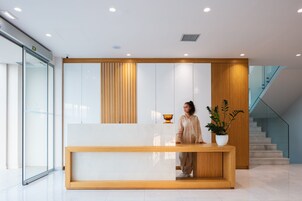 Egy modern, fa borítással ellátott recepciós pult, egy virágtál és a háttérben egy lépcsőház.