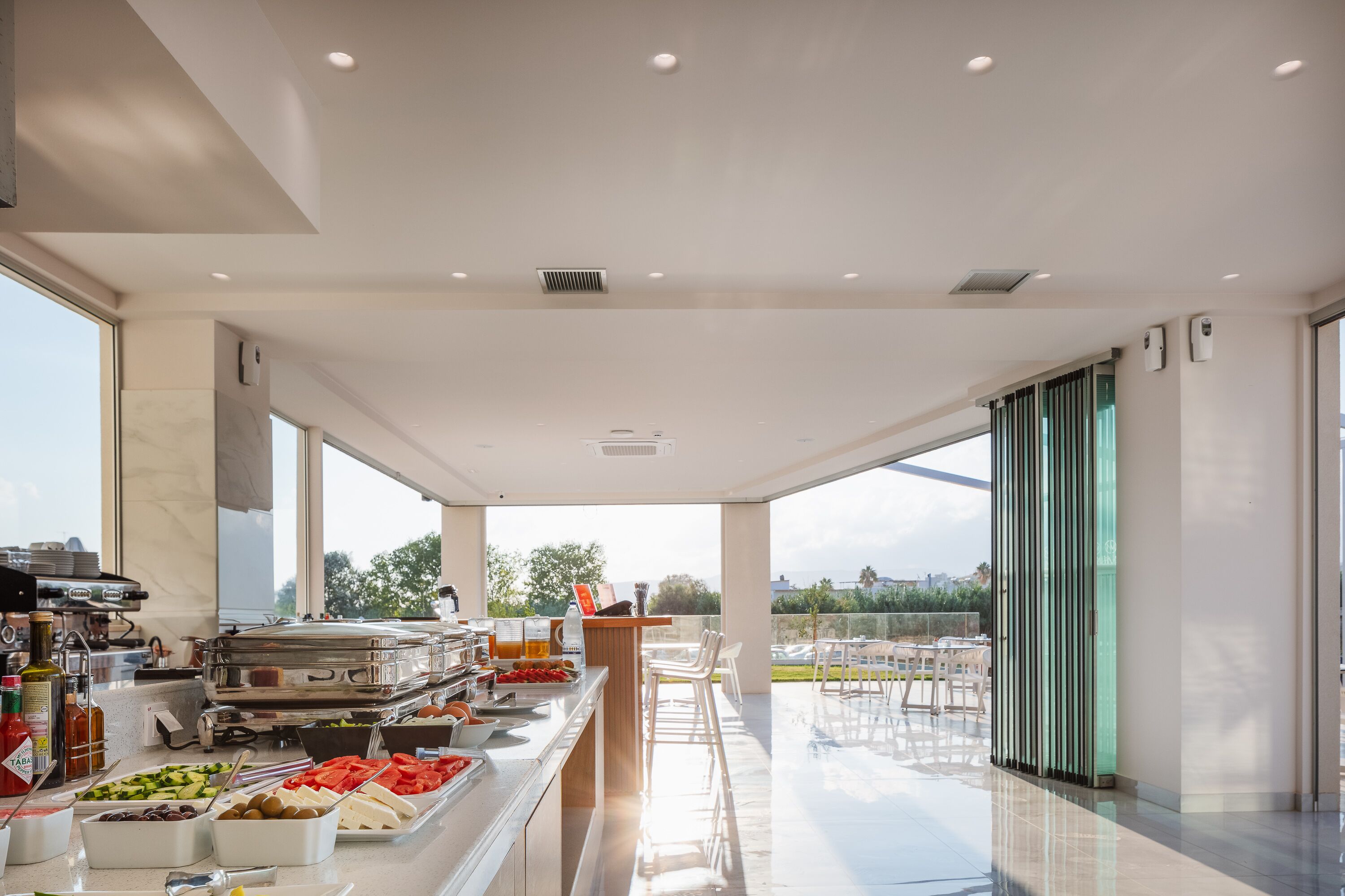 A modern kitchen with a buffet setup, large windows, and a view of the outdoors.