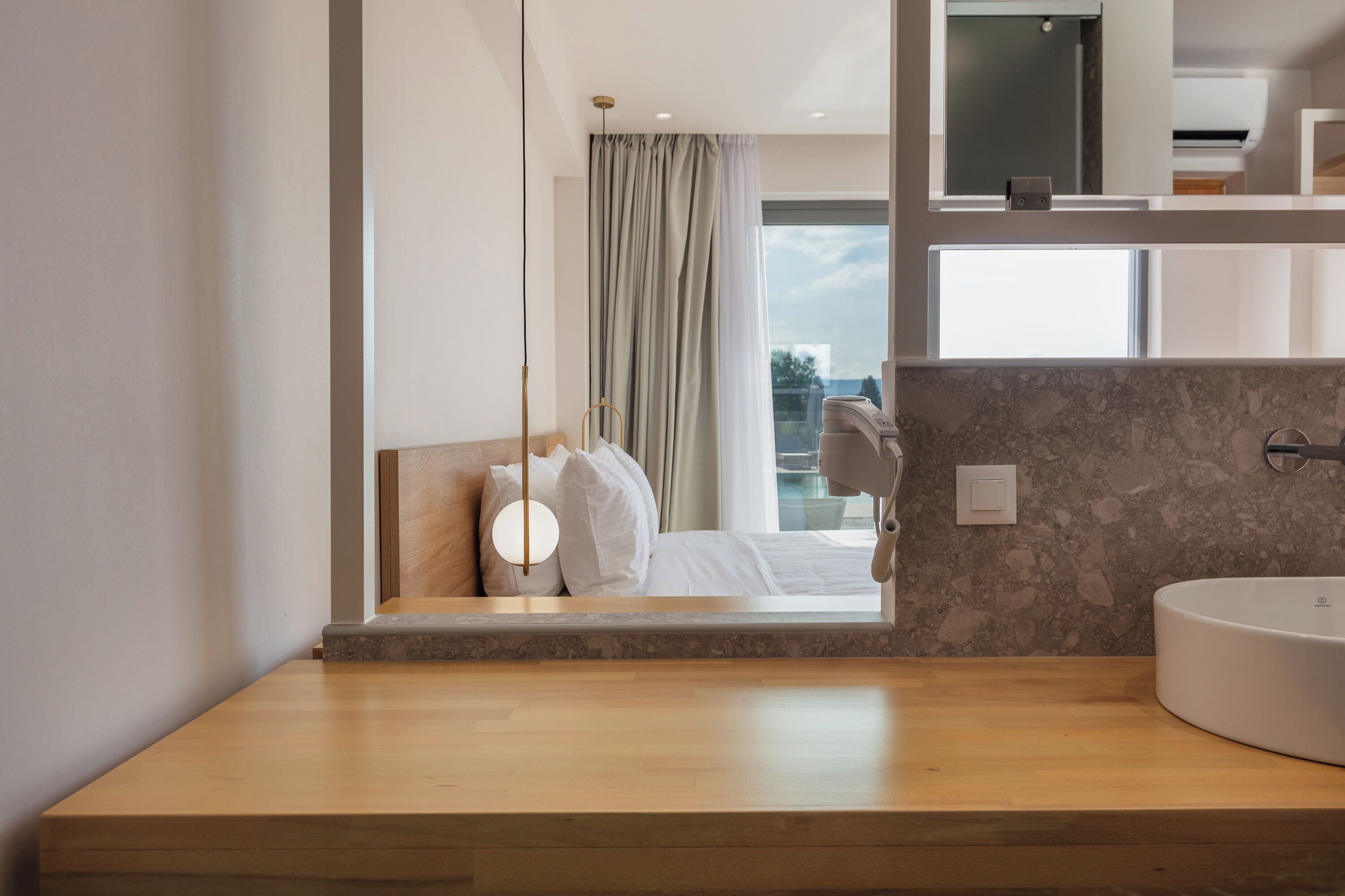 Un baño moderno con tocador de madera, un lavabo grande y un espejo.