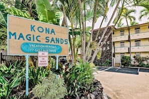 Un panneau indiquant l’accès à Kona Magic Sands, avec un autre panneau interdisant le stationnement des voitures et l’accès aux restaurants sur la plage.