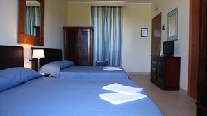 A hotel room with two beds, a desk, a television, and a wardrobe. - Hotel Villa Giulia (Porto Azzurro)