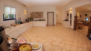 A spacious room with a buffet setup, a dining area, and a television. - Hotel Villa Giulia (Porto Azzurro)