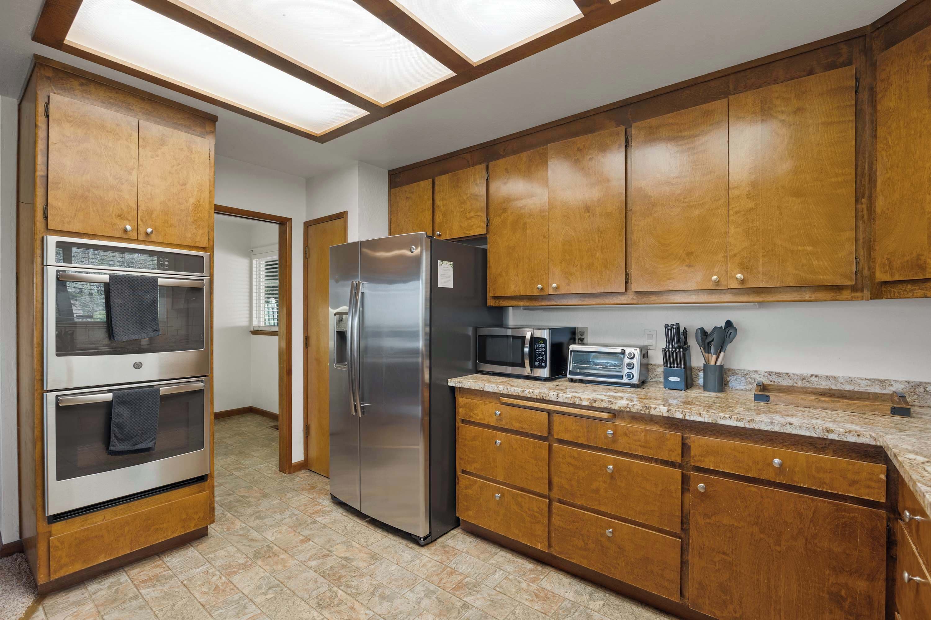 A kitchen with wooden cabinets, stainless steel appliances, and a tiled floor.