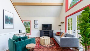 A living room with a TV, two sofas, a coffee table, and a large plant. - Hot Tub, Fire Pit, Deck, Grill, WiFi, Dog-Friendly (Gerrardstown)