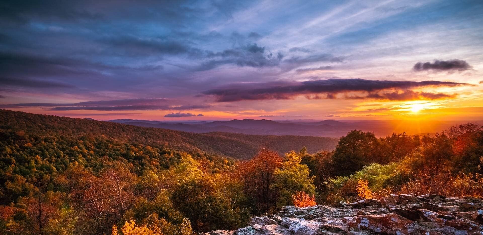 Eine Berglandschaft mit Herbstlaub und Sonnenuntergang.