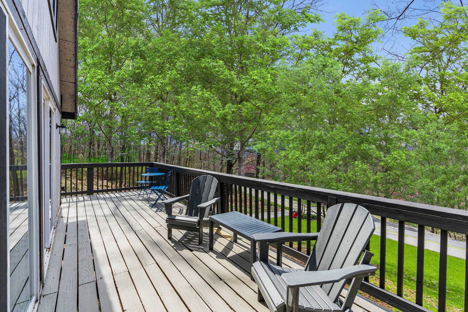 A wooden deck with outdoor seating, surrounded by trees.