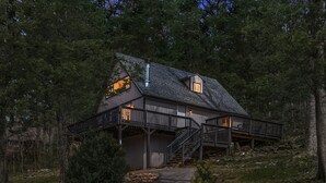 Une cabane rustique dotée d’une terrasse en bois, d’une cheminée et de fondations en pierre.