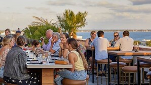 Een buiten eethoek met tafels en stoelen, met uitzicht op een waterpartij.
