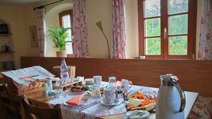 Una mesa de comedor servida con diferentes platos, una tetera y una planta en maceta.