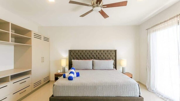 Une chambre avec un grand lit, un ventilateur de plafond, des lampes de chevet et une armoire.