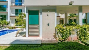 A modern hotel with a swimming pool, a covered entrance, and a well-maintained garden. - Spacious Retreat- Pool, Gym, 3 Balconies & Parking (Playa del Carmen)