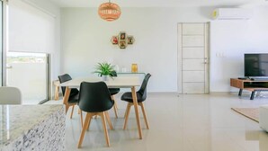 A modern living room with a dining area, a television, and a door. - Spacious Retreat- Pool, Gym, 3 Balconies & Parking (Playa del Carmen)