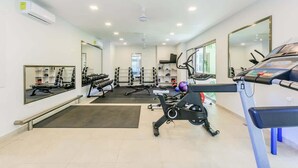 Une salle de sport équipée de machines d’exercice, de miroirs et d’un tapis de course.