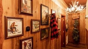 Un couloir en bois orné de tableaux encadrés, un lustre et un sapin de Noël.
