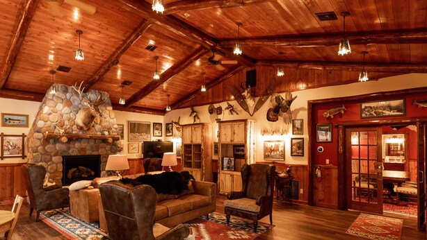 Un intérieur rustique avec une cheminée en pierre, des meubles en cuir et des poutres en bois.