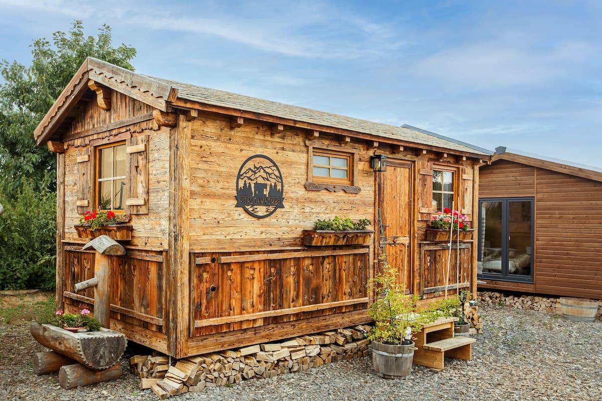 A wooden cabin with a mountain emblem, wooden steps, and flower planters.