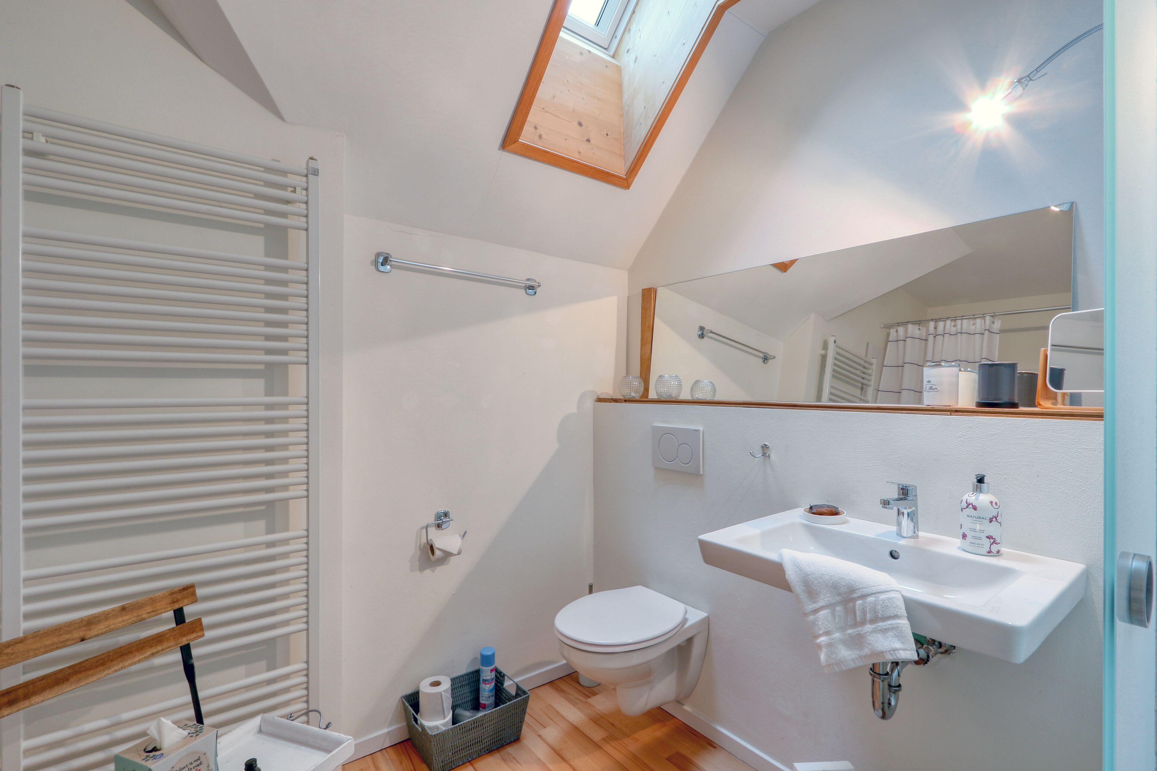 Un bagno moderno con una finestra sul tetto, un water, un lavabo e uno specchio.