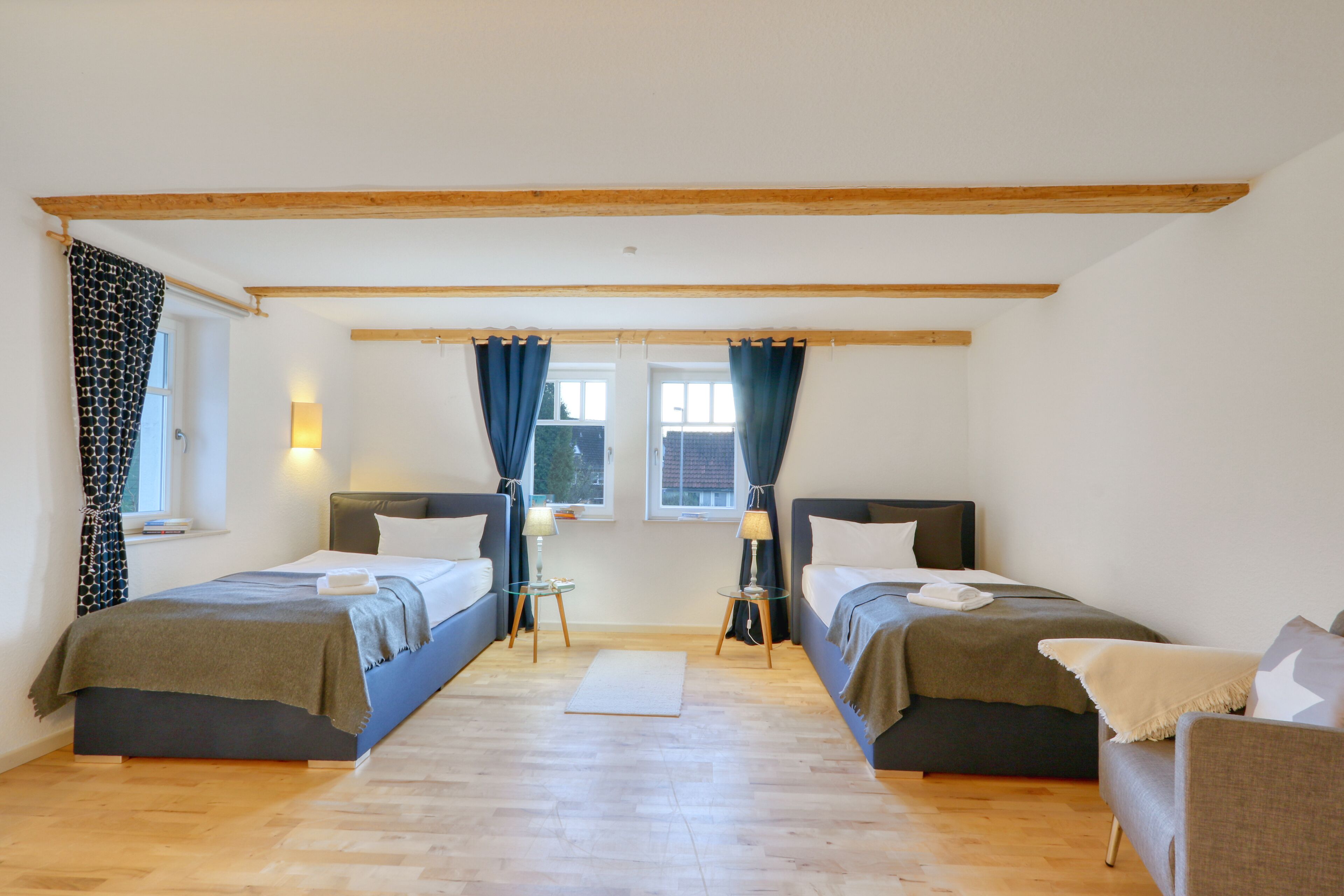 Une chambre avec deux lits, un canapé et une fenêtre avec des rideaux.