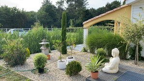 Un jardin agrémenté de diverses plantes, d’une statue et d’une clôture blanche.