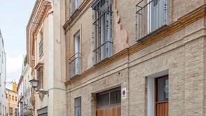 A narrow cobblestone street lined with historic brick buildings, featuring balconies and large wooden doors. - Genteel Home Goyeneta (Seville)