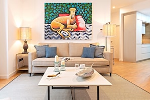 A modern living room with a sofa, coffee table, and artwork on the wall.