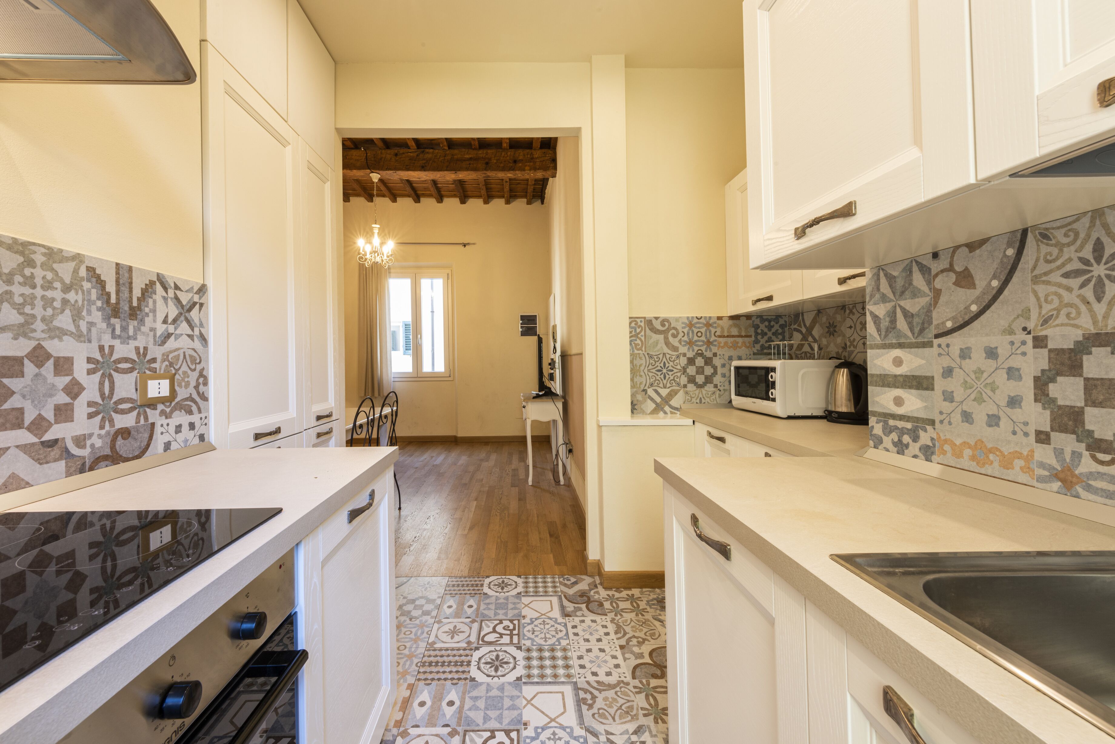 Una cocina con baldosas estampadas, un microondas y una estufa.