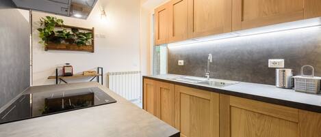 A modern kitchen with wooden cabinets, a stainless steel refrigerator, and a built-in stove.