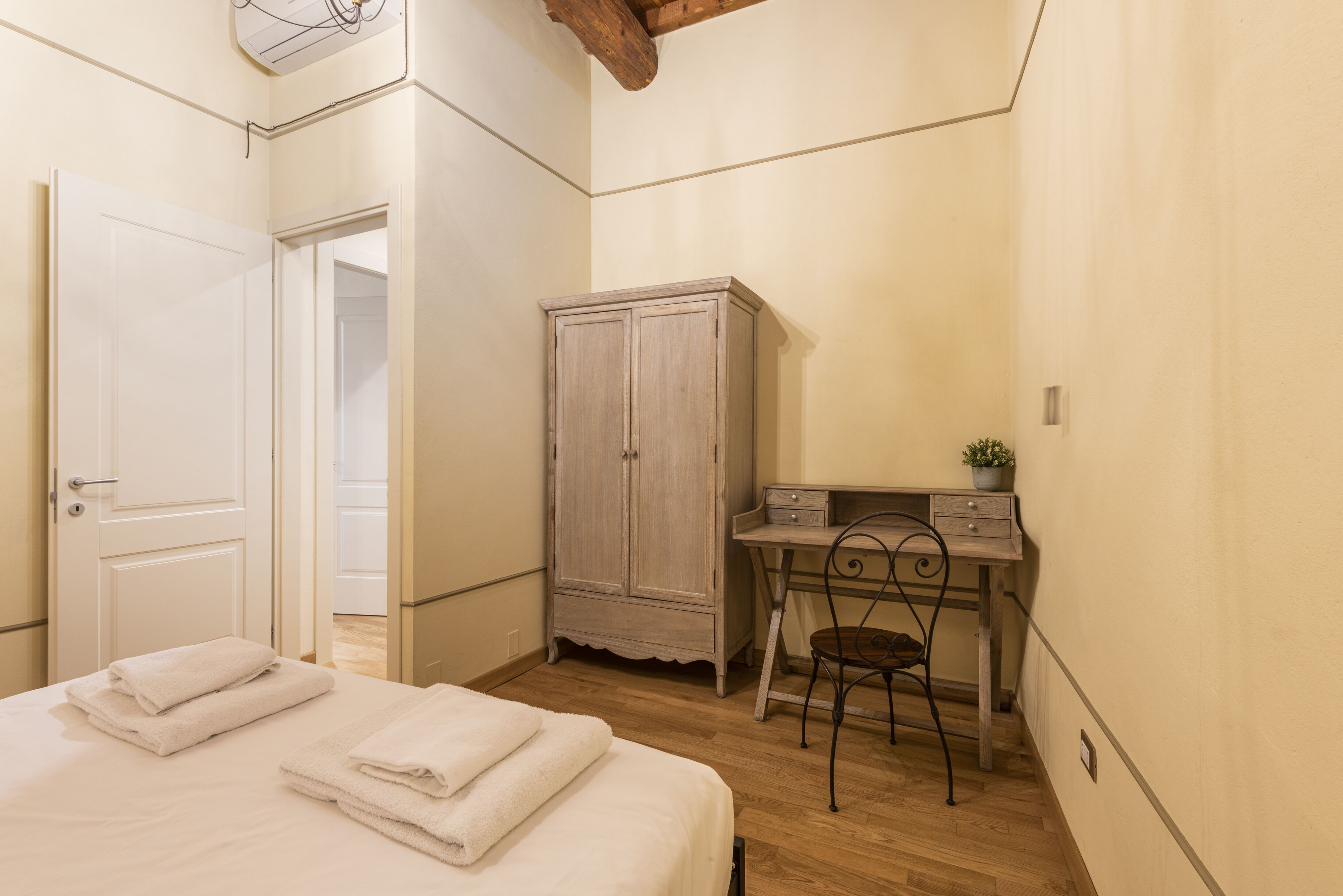 A bedroom with a bed, a desk, a wardrobe, and a chair.