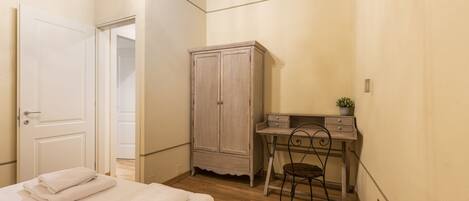 Un dormitorio con cama, escritorio, armario y una silla.