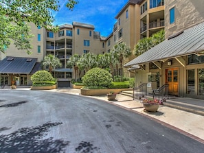 A multi-story hotel with a central courtyard, featuring a covered entrance, outdoor seating, and well-maintained landscaping.