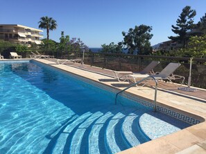 A swimming pool with clear blue water, surrounded by lounge chairs and a palm tree. - CANNES: Luxurious studio in the Croix des Gardes residential neighborhood, with a pool (Cannes)