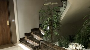 Una scala moderna con ringhiera in vetro, una porta in legno e una pianta in vaso.
