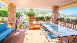 A covered patio with a table and chairs, stone pillars, and potted plants. - S'Omu and Assunta 1P by All4sardinia  (Cardedu)
