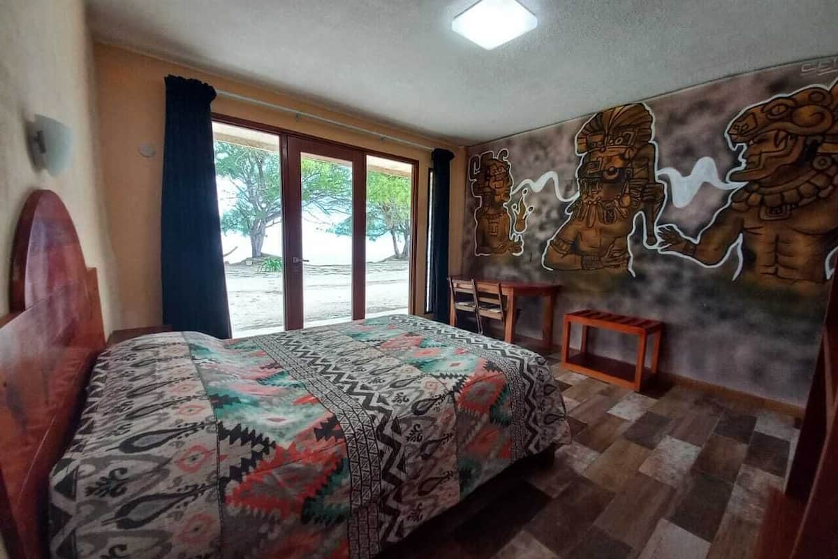 Un dormitorio con cama, escritorio y un mural en la pared.
